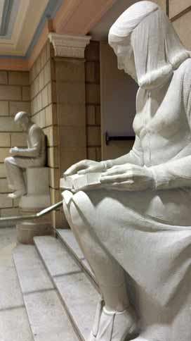 Sculpture of a girl in the foreground with the sculpture of a boy in the background.