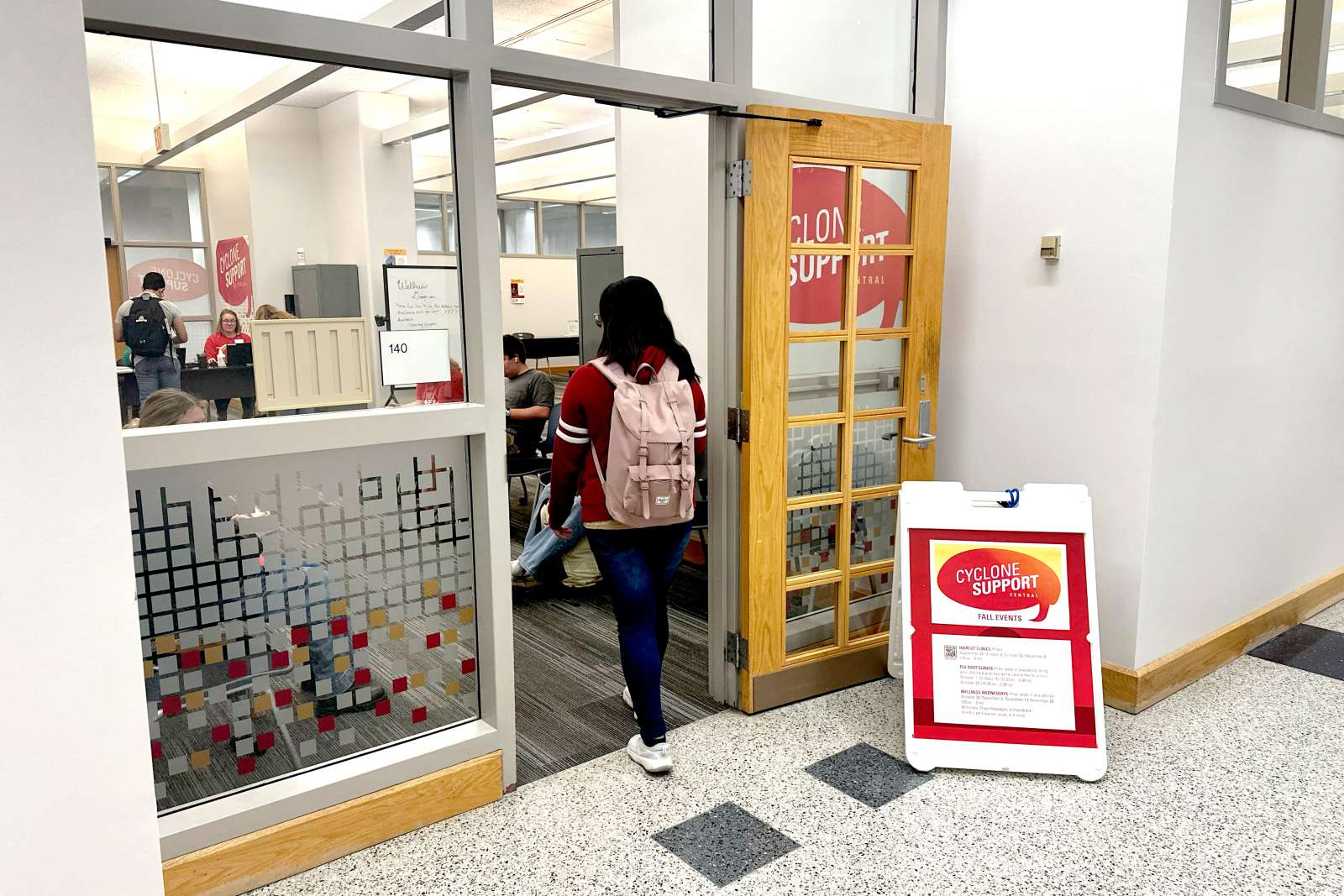 student wearing a backpack walks into a room with flu shot check in